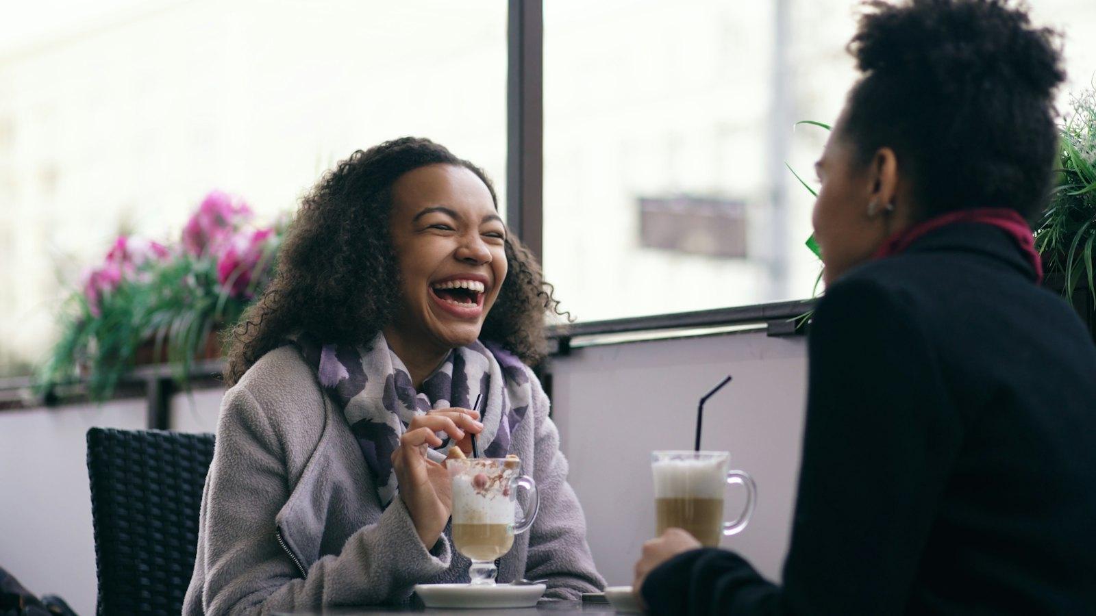 Two friends laughing over coffee